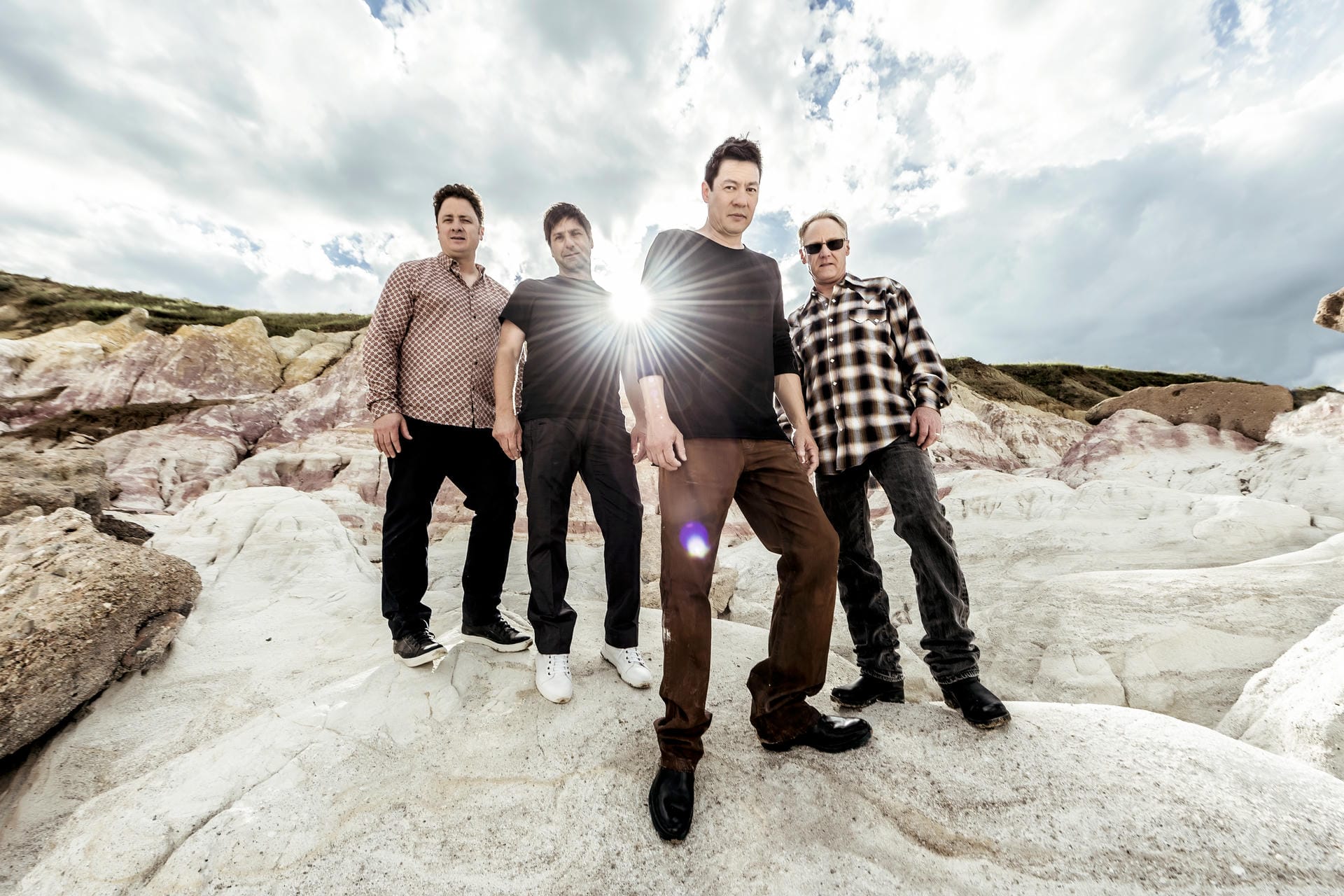 Four people standing on a rocky landscape with a bright light source in the middle.