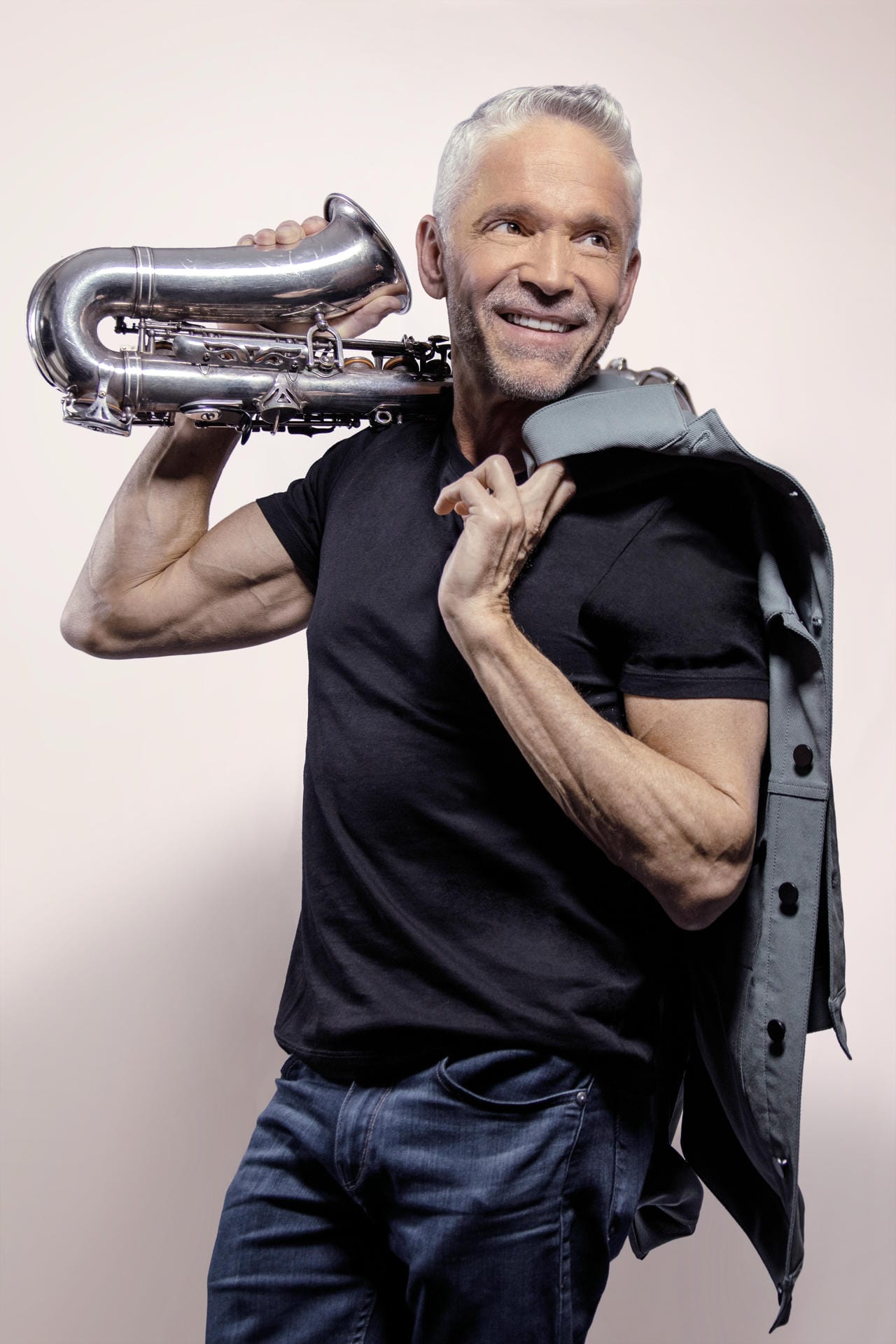 Man holding a tuba against a plain background
