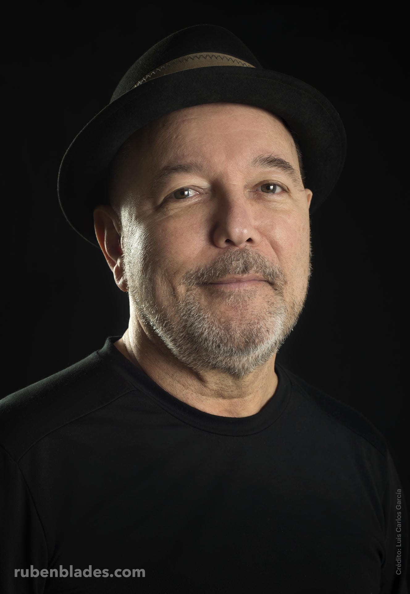 Man wearing a black hat and black shirt against a dark background