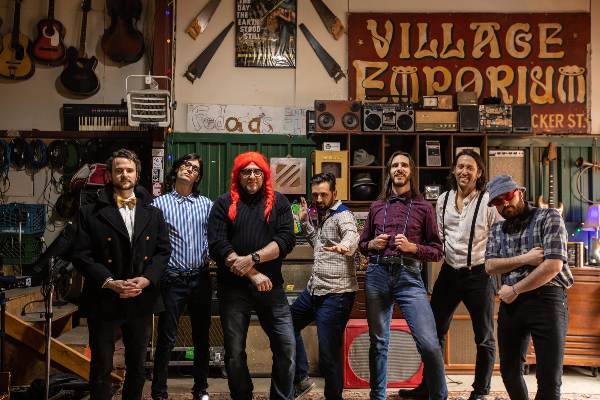 Group of people posing together in a music store with 'Village Emporium' sign.