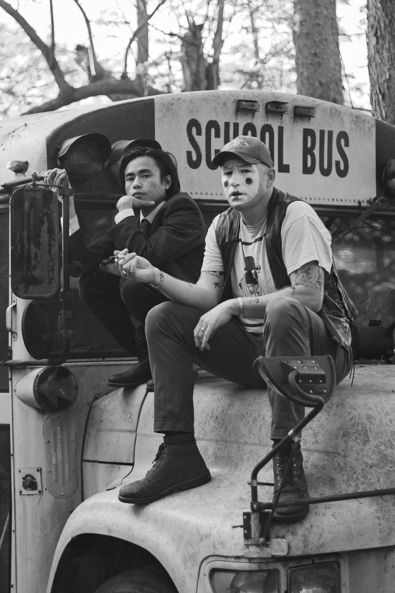 Two individuals sitting on a school bus with a black and white filter.
